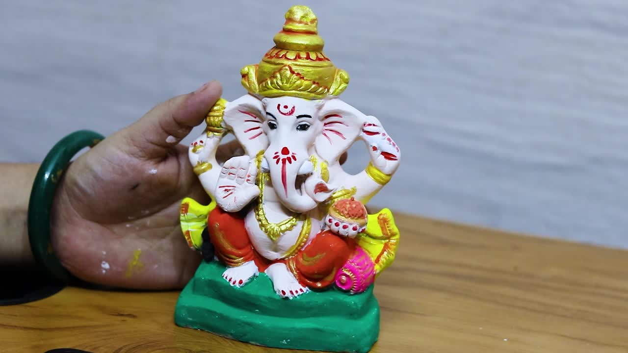 devoto che colora l'idolo del dio indù ganpati in occasione di ganesh chaturthi