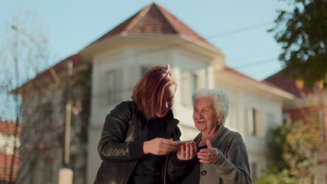 Two women of different generations looking at a smartphone outdoors