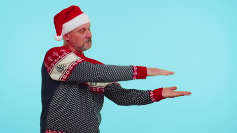 Man-wears-red-Christmas-deer-sweater-showing-thumbs-up-and-pointing-at-on-blank-advertisement-space