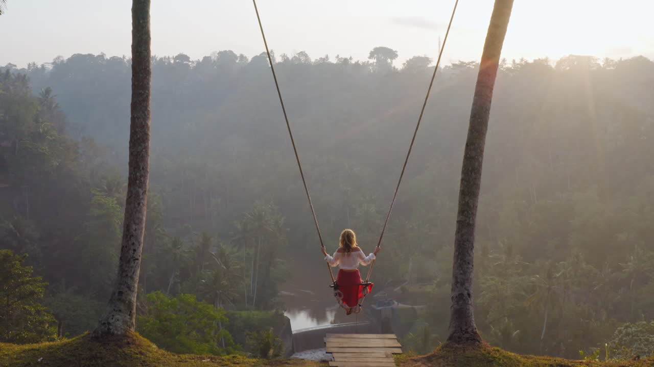 vista aérea mujer balanceándose sobre la selva tropical al amanecer sentada en el columpio con vista al río disfrutando de divertirse en las vacaciones libertad de viaje