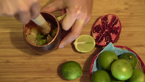 barman swirling crushed lime cocktail fruit drink on wooden counter