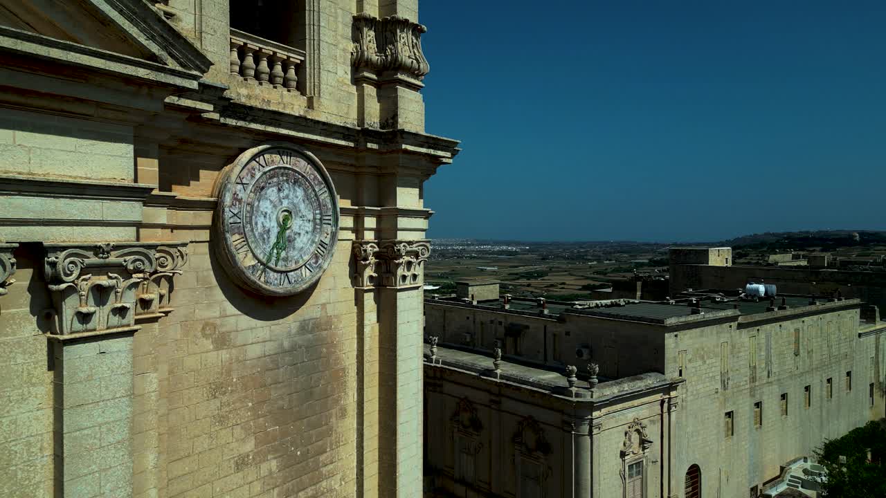 Close aerial pass of St Paul’s Cathedral clock tower with detailed stonework and skyline behind, weathered stone