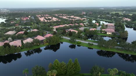 river and luxury houses with orange roof of town in florida, usa. aerial wide shot. green trees on cloudy day. streets and path between exclusive homes
