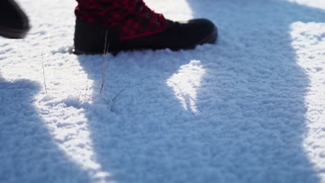 red plaid snow boots walk through untouched snow in slow motion