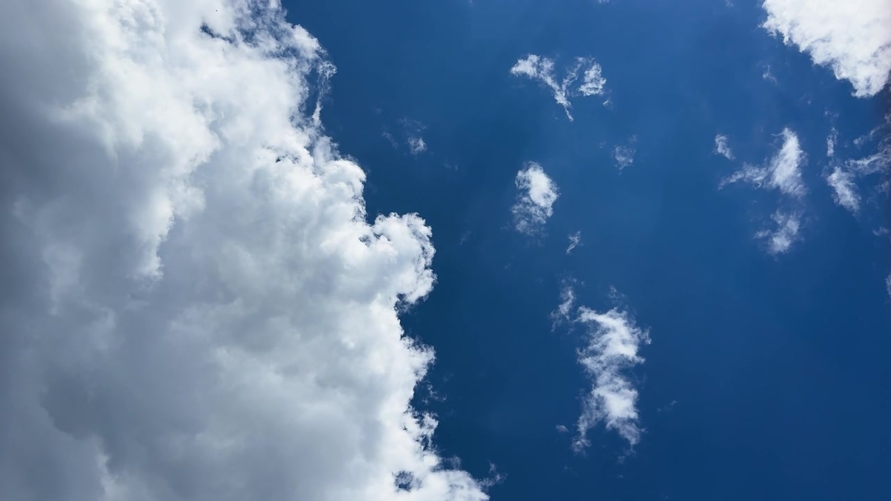 Ampia inquadratura orizzontale di una grande nuvola cumuliforme che riempie un cielo azzurro brillante.
