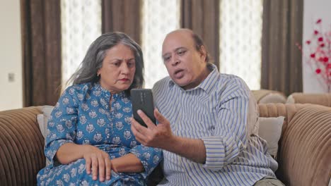 Upset-old-Indian-couple-talking-to-someone-on-video-call