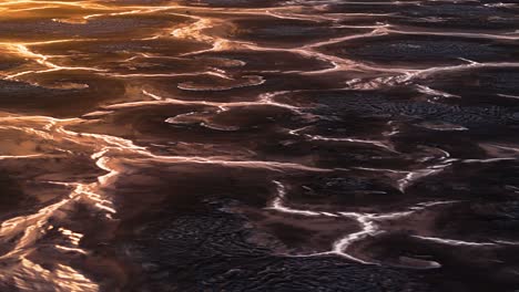 aerial parallax around braided streams of water between large mounds, natural earth wasteland textured pattern