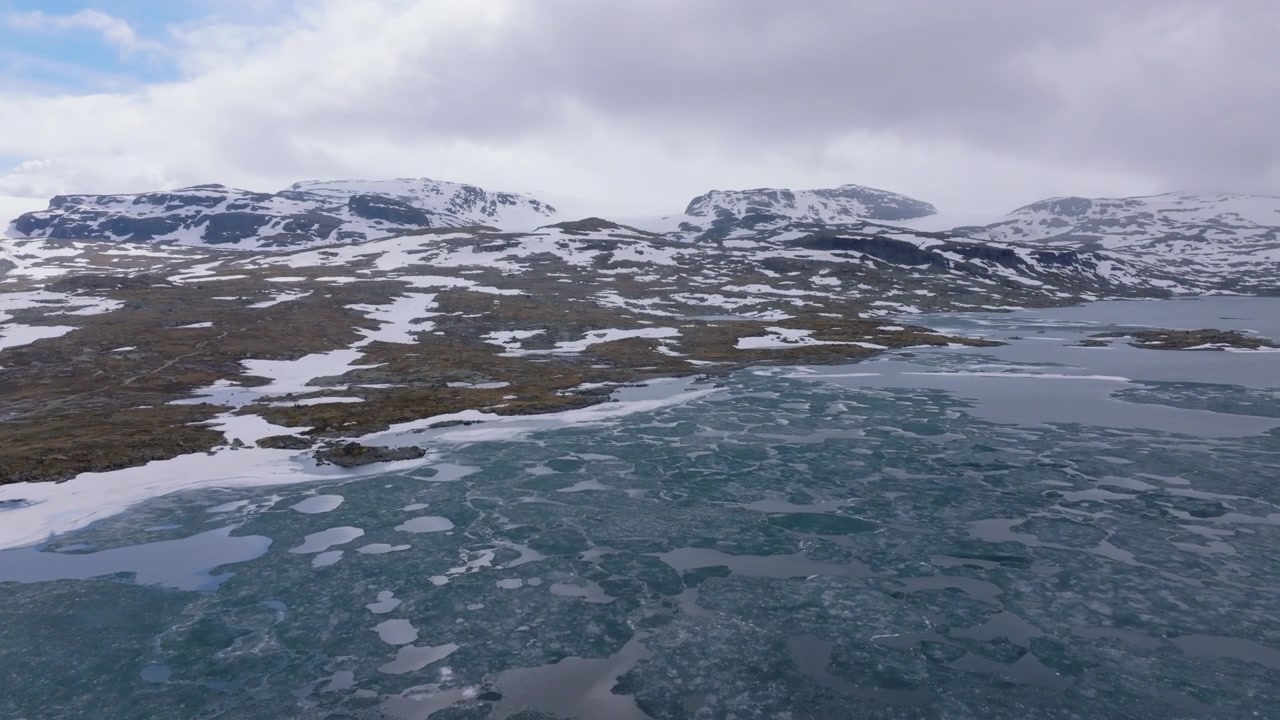 Droneoptagelse, der afslører udsigten fra flydende is på Finsevatnet til den majestætiske Hardangerjøkulen-gletsjer i det norske højland.
