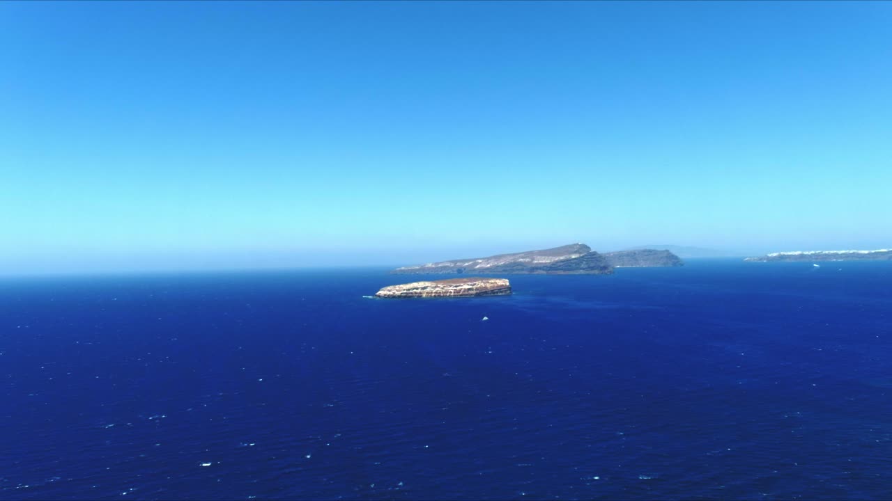 산토리니 그리스에서 수평으로 움직이는 먼 열대 섬을 향한 공중 4k 푸른 바다와 하늘 꼭대기