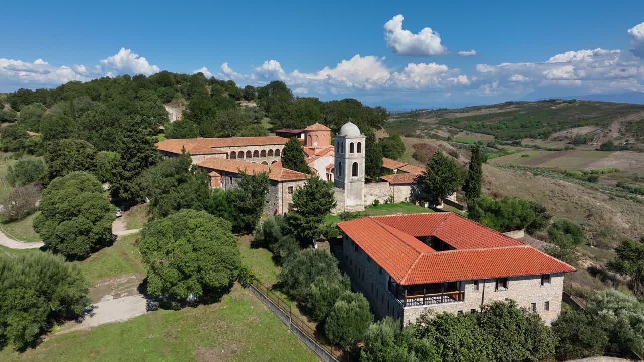 Ancient ruins and monastery at Apollonia, Albania surrounded by green hills in bright daylight, aerial establishing descend