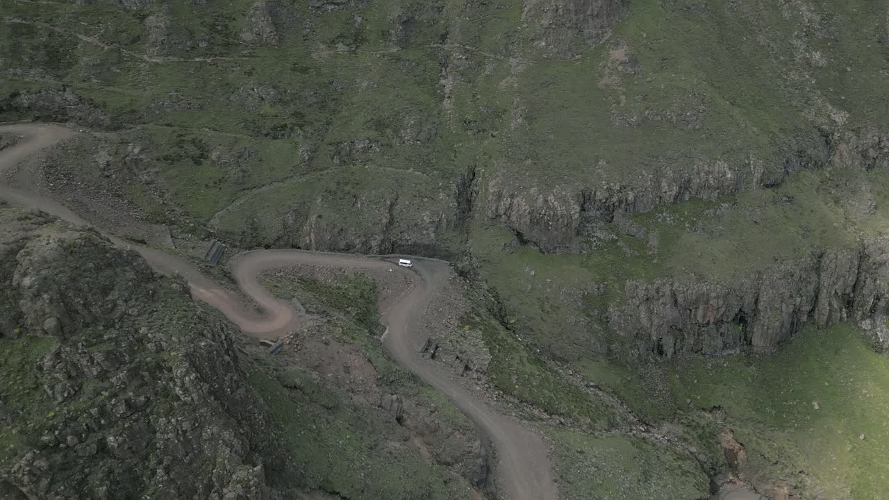 vista de pájaro: el vehículo desciende por las curvas de tierra áspera de sani pass