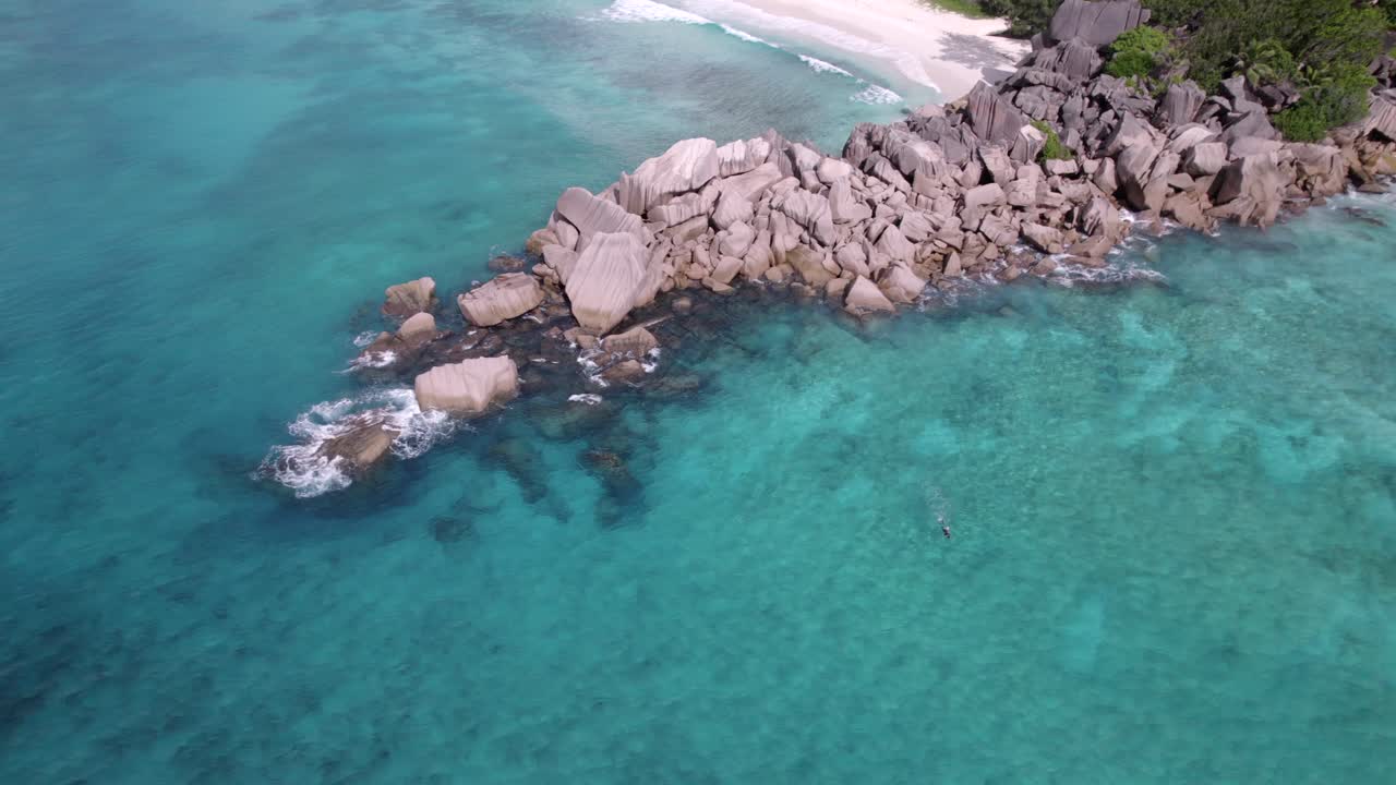 Vue aérienne de la nature incroyable depuis la plage de Grand Anse et Petite Anse, pierres de granit le long de l'eau, une personne seule faisant de la plongée avec tuba, vagues déferlantes, nature intacte, La Digue, Seychelles 30fps 005