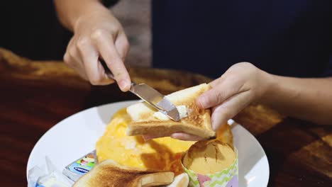 person spreading butter on slices of toast