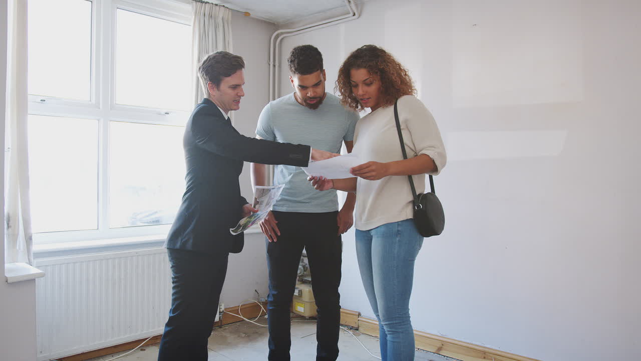 Couple primo-accédant examinant un rapport d'expertise avec un agent immobilier.