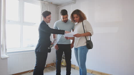 couple buying house for the first time looking at survey with realtor