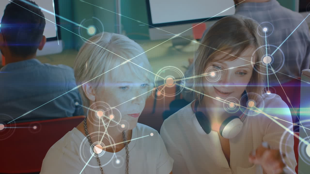 사무실에서 디지털 태블릿을 사용하는 두 백인 여성에 대한 연결망의 반이는