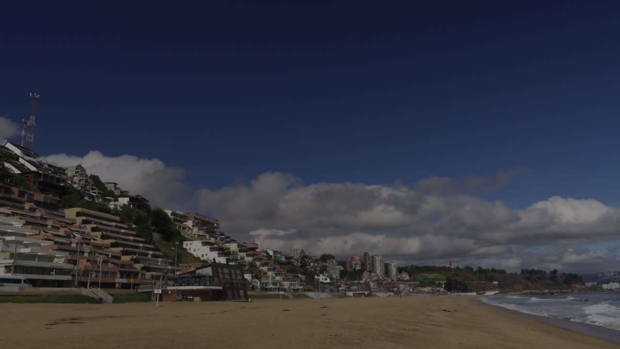 Coastal town with buildings on a hillside overlooking a sandy beach and the ocean