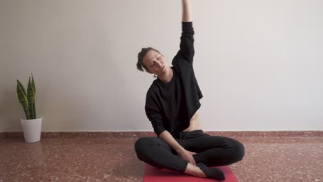 Altrenativa-woman-doing-stretching-at-home-sitting-on-the-floor-and-with-decorative-plants