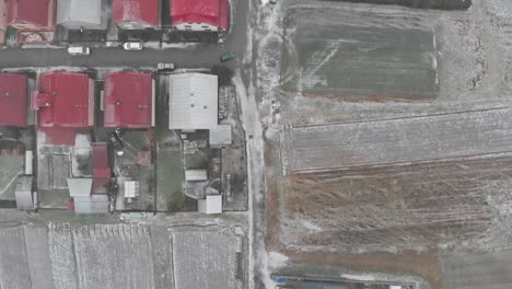 Top-down-overhear-Aerial-over-residential-area-and-fields-with-car-driving-through-street