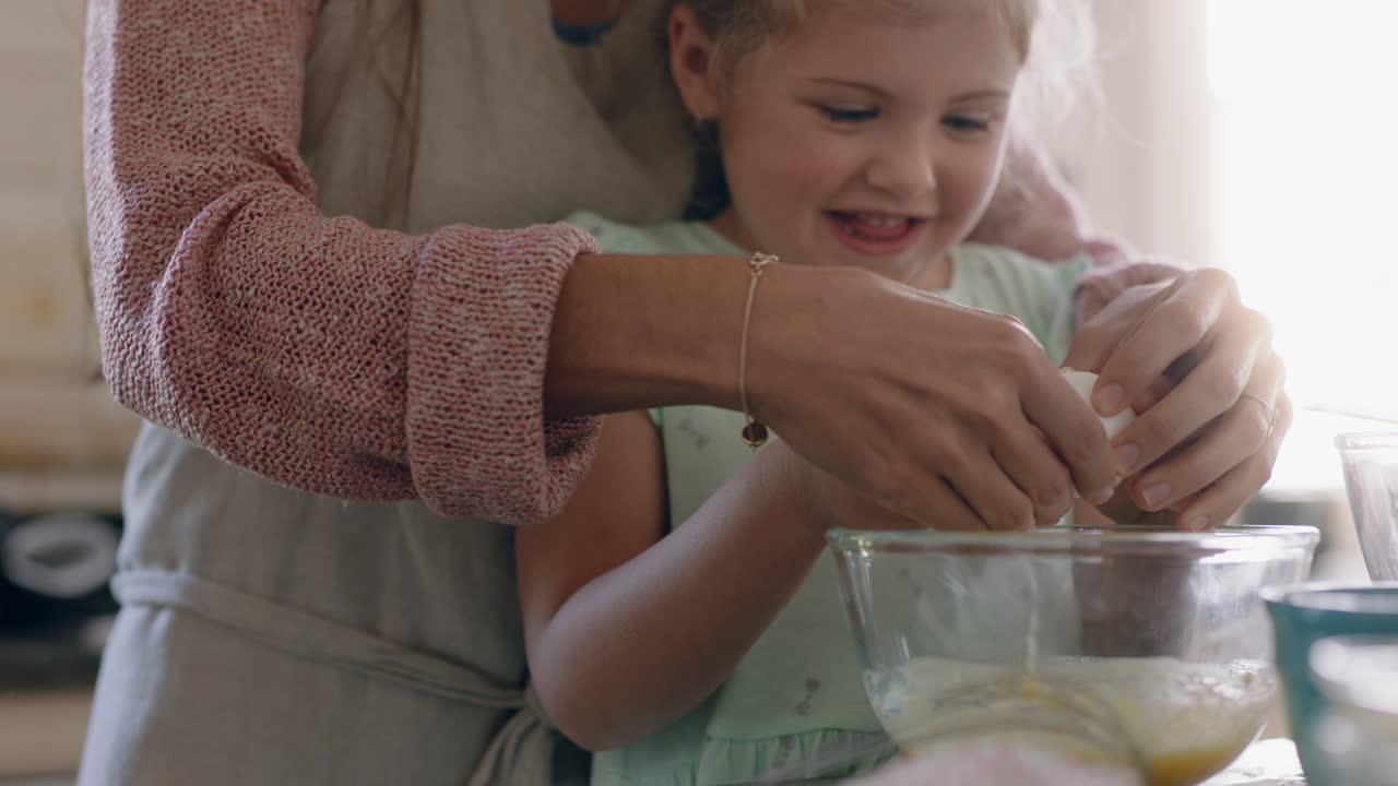 cute little girl helping mother bake in kitchen mixing ingredients breaking eggs into bowl preparing recipe at home with mom