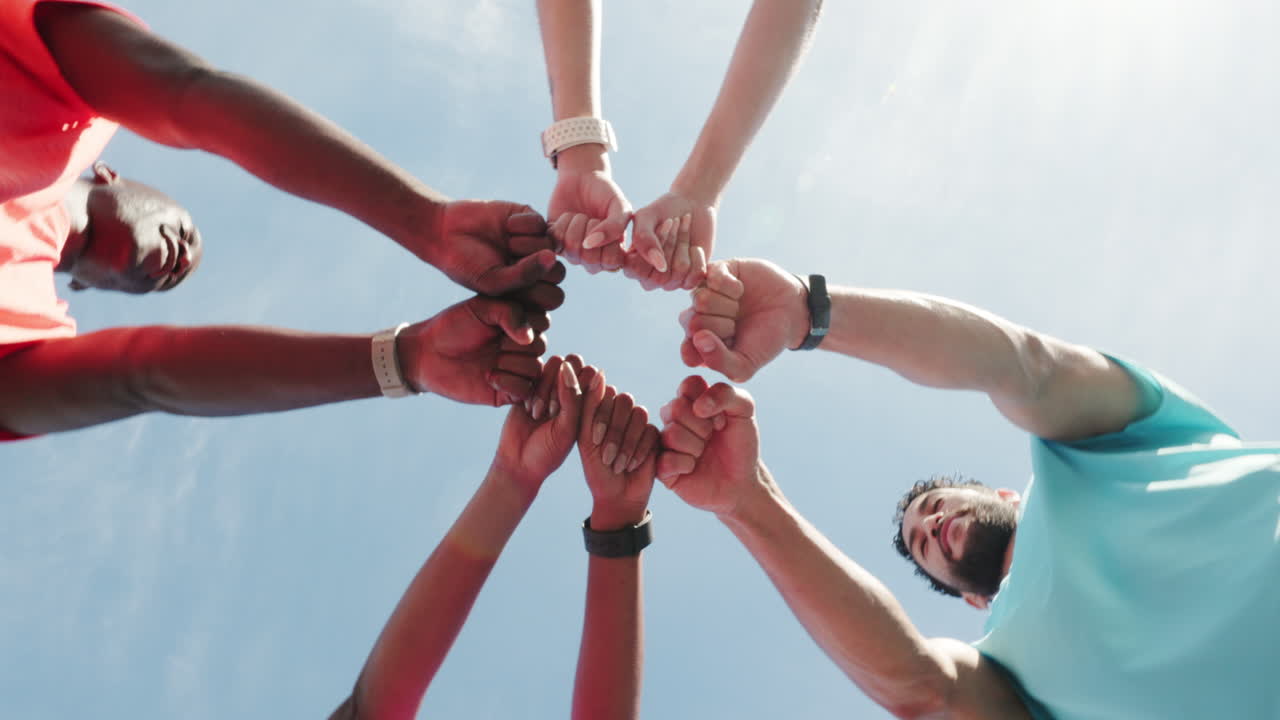 Gruppo di amici di diverse origini che uniscono i pugni in cerchio.