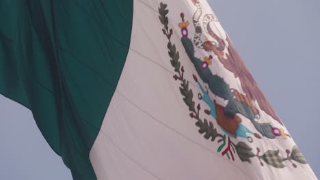 mexico flag against blue sky waking on windy day, slow motion view