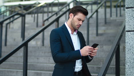 closeup man typing on phone outdoor at stairs. man using mobile phone outside