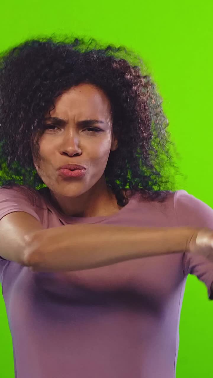 Donna afroamericana che fa smorfie divertenti mentre telefona e balla.