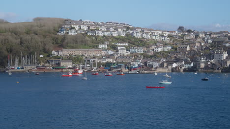 Gig-Boat-Crew-Rowing-Along-Fowey-River-with-Cornish-Polruan-Fishing-Village-in-Background---wide-shot