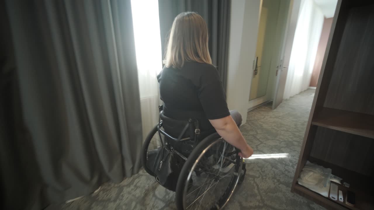 una mujer en silla de ruedas navega a través de una habitación de hotel, destacando alojamientos accesibles y diseño inclusivo. la imagen hace hincapié en la movilidad, la independencia y la infraestructura de hospitalidad moderna.