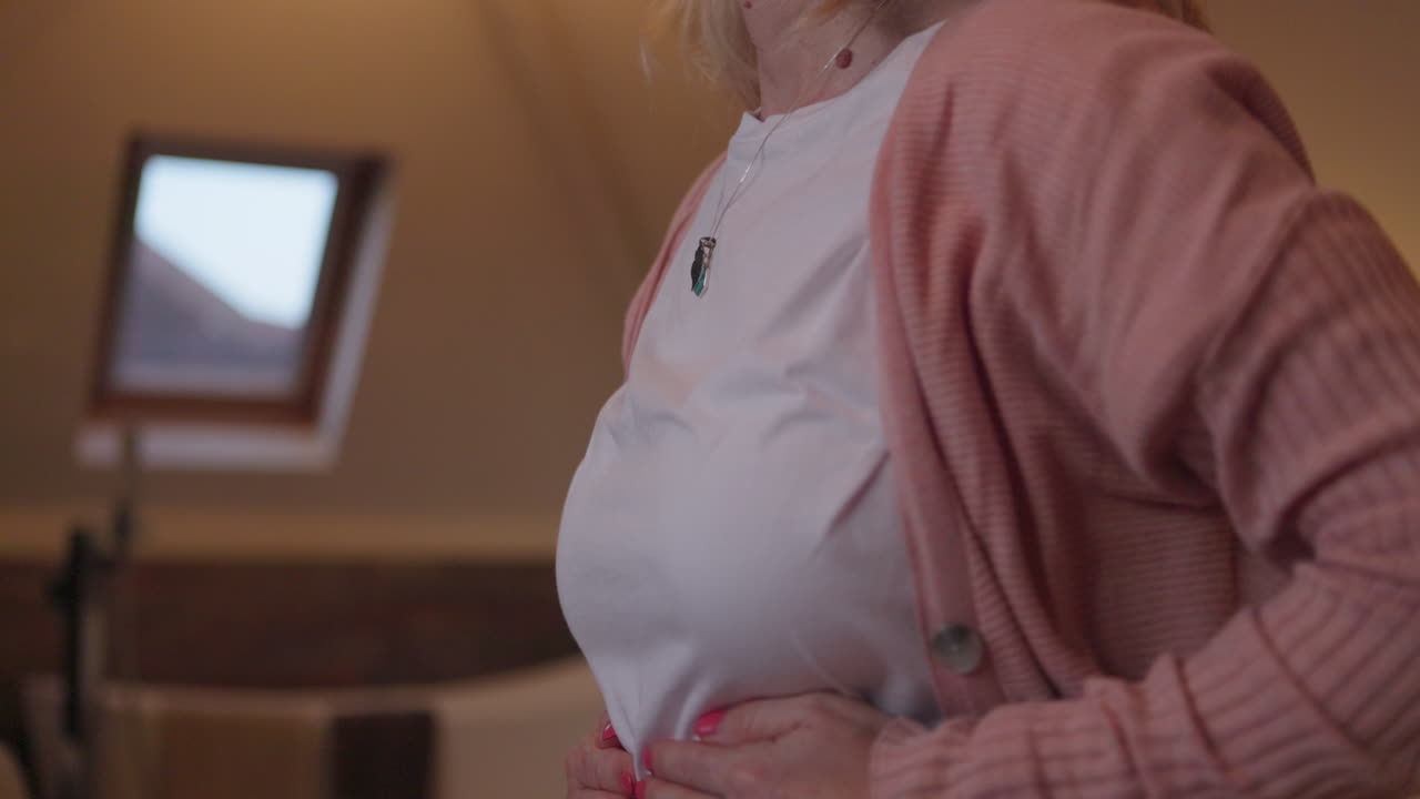 Woman in pink cardigan with abdominal pain