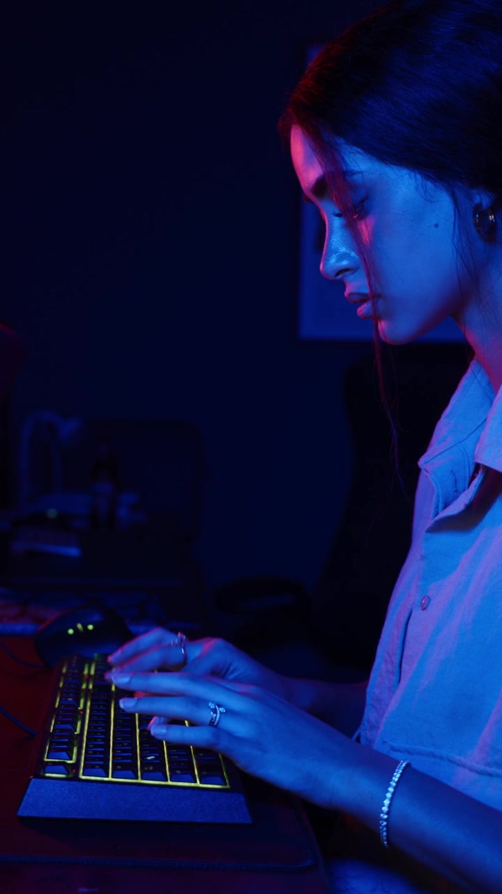 Young Woman Typing on Illuminated Keyboard in Dark Room
