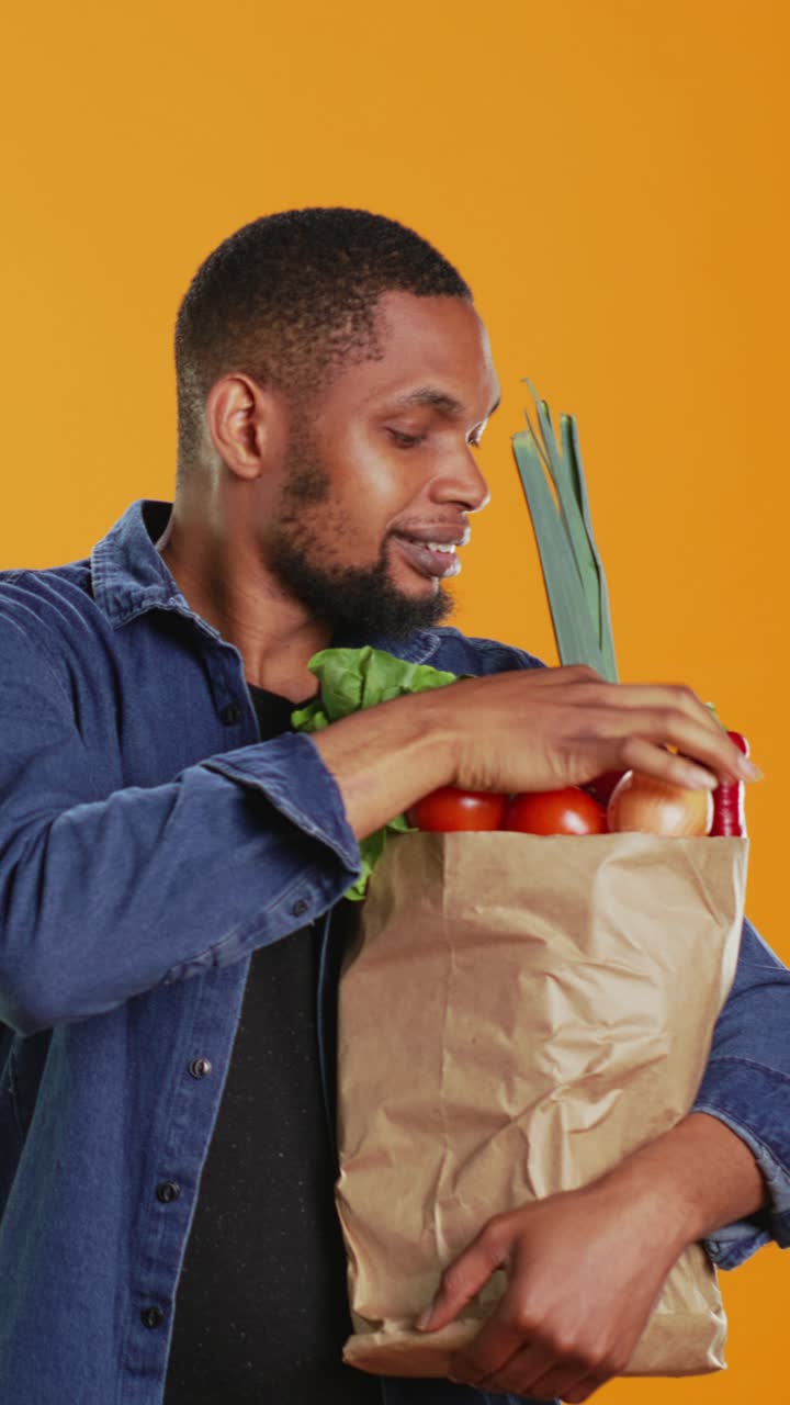 Uomo felice che tiene in mano una borsa di carta con verdure fresche