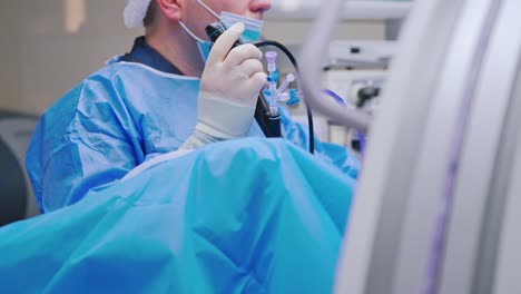 Woman assistant helps surgeon. Doctor together with a nurse use new medical equipment during laparoscopic surgery in the operating room.