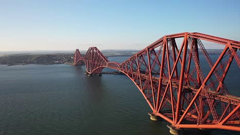 Cinematic-Aerial-Flyby-of-The-Firth-of-Fourth-Railway-Bridge-in-South-Queensferry-Near-Edinburgh,-Scotland-on-a-Clear-Summer-Evening