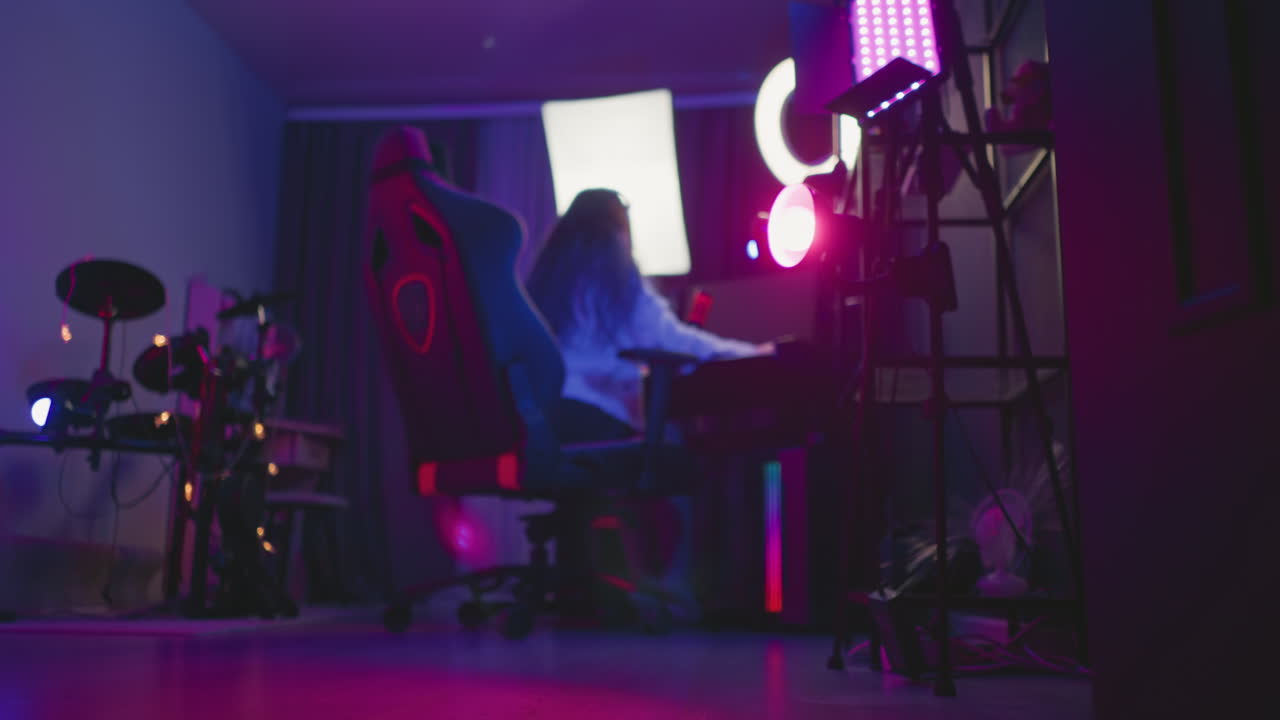 freelancer seated in gaming chair inside modern equipped studio filled, while using mouse and keyboard surrounded by musical gear and recording setup