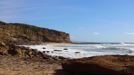 el océano se encuentra con un acantilado con olas golpeando las rocas en un día soleado