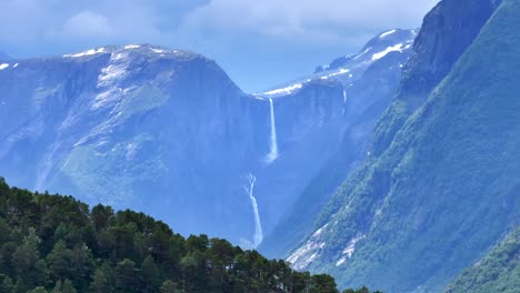 el avión no tripulado se acerca y se eleva lentamente detrás de las montañas y mardalsfossen en eikesdal aparece a la vista