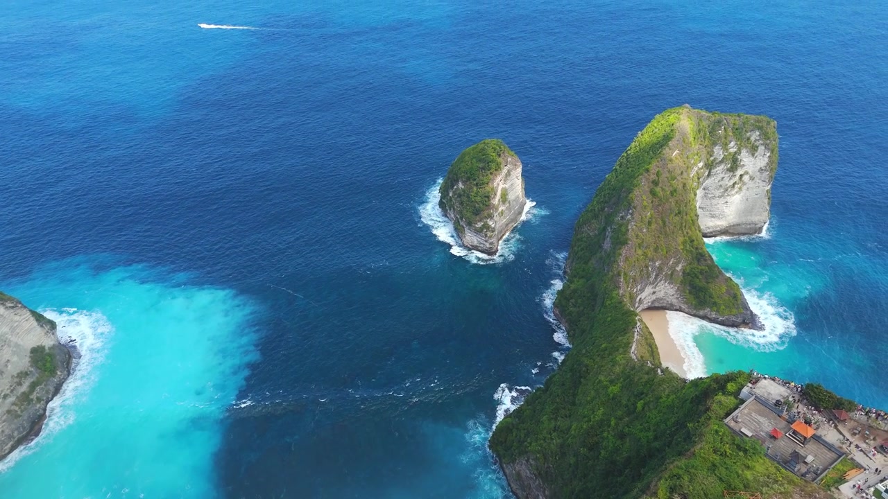 La playa Kelingking y su famoso acantilado T Rex se elevan sobre calas turquesas en un suave paneo aéreo.