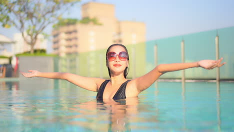 Una-Mujer-Hermosa-En-La-Piscina-De-Un-Resort-Levanta-Los-Brazos-Para-Saludar-A-La-Mañana