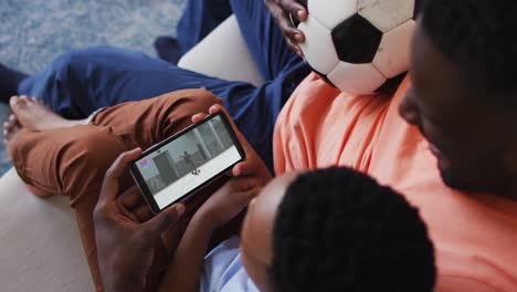 composite of father and son at home watching athletics running event on smartphone