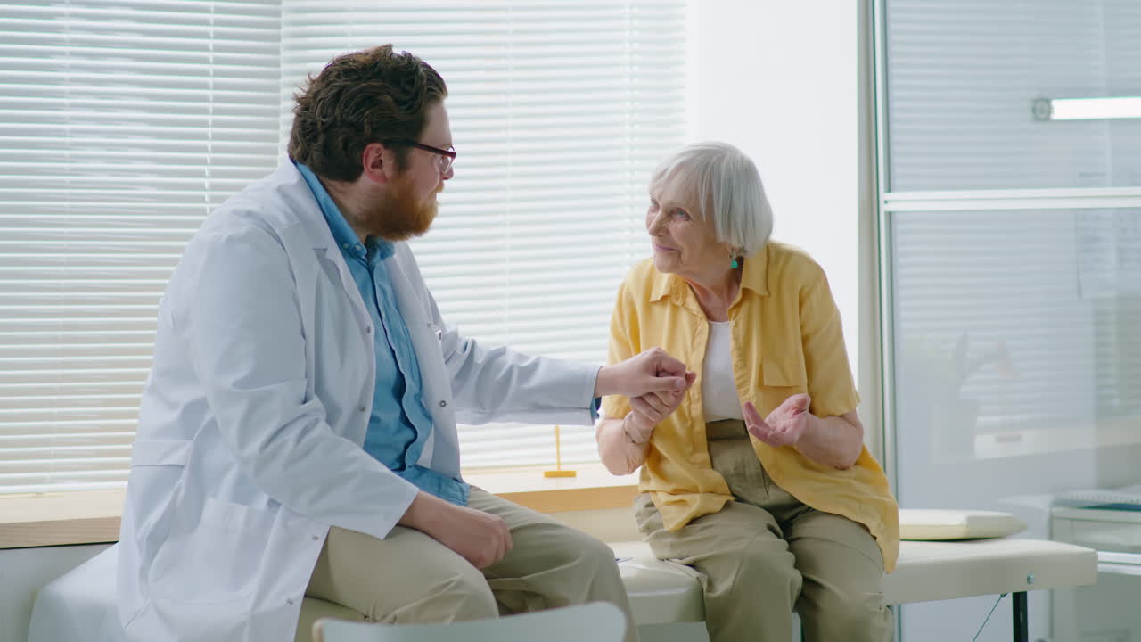 Doctor Holding Hand with Elderly Woman and Supporting Her