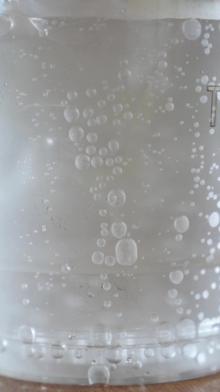 Macro di bollicine che salgono in un bicchiere di acqua frizzante.
