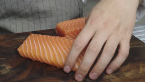 cutting salmon into three slices on wooden cut board