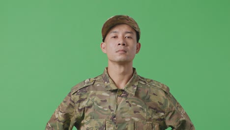 Close Up Of Asian Army Soldier Standing Against On Green Screen Background Studio. Brave Young Servicemen Wearing Camouflage Military Uniform