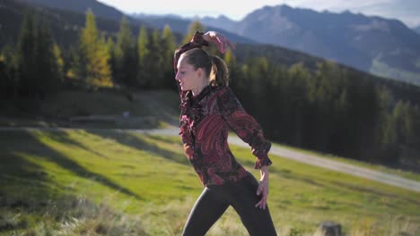 slow motion orbiting gimbal shot of a young woman dancing on a wooden platform at sun set, golden hour