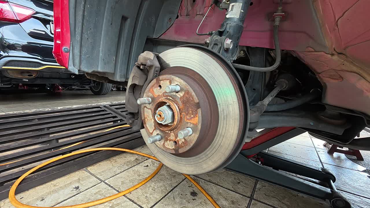 The car's exposed disk brake is ready for servicing at the workshop. The wheel has been removed for maintenance, ensuring optimal braking performance and safety.