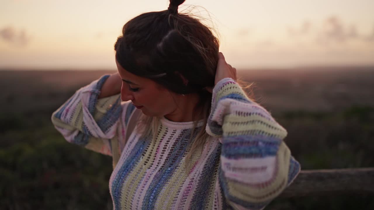 disparo en cámara lenta de un modelo jugando con su cabello durante el atardecer