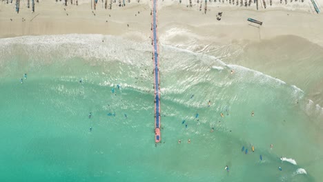 directly above floating jetty on shore of lombok with beginner surfers in water