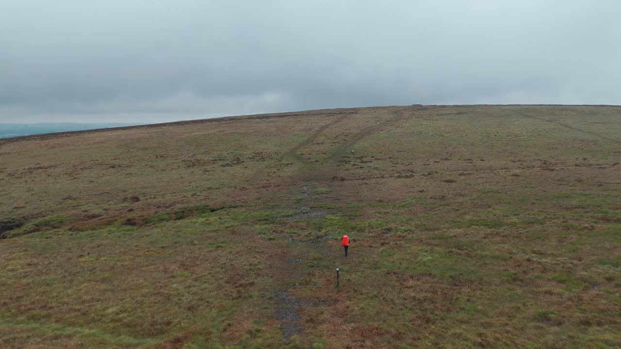 Wide angle view of tourist with orange backpack is trekking towards Five stones in England